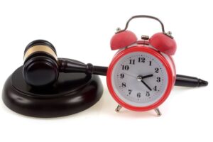 Judge's gavel on its plinth next to a bell clock in close-up on white background