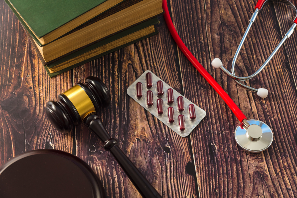 Gavel, medical books, pills, and a stethoscope on a table representing medical negligence issues.