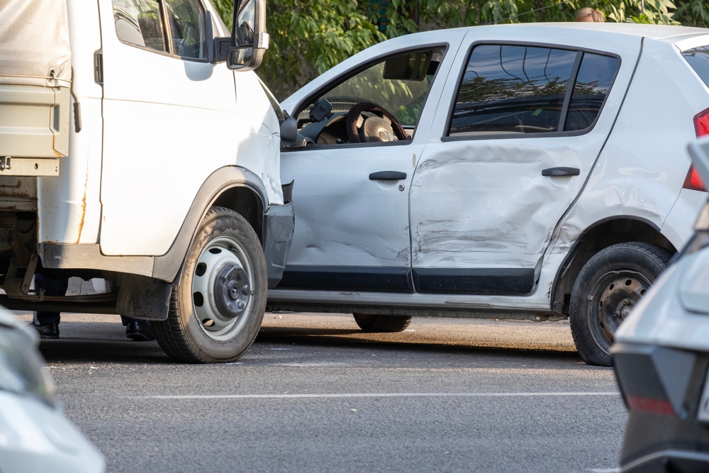 White van with front-end damage after striking the side of a car at an intersection.